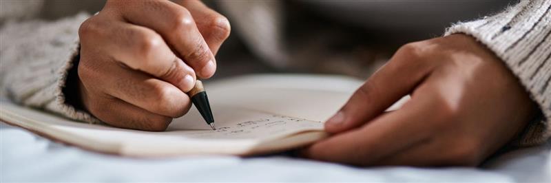 A person writing with pen on paper