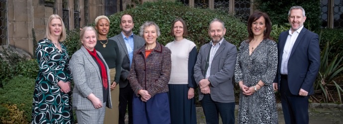 Cadent's Customer Challenge Group members standing together, posing at the camera in front of a traditional stone building with greener in the background