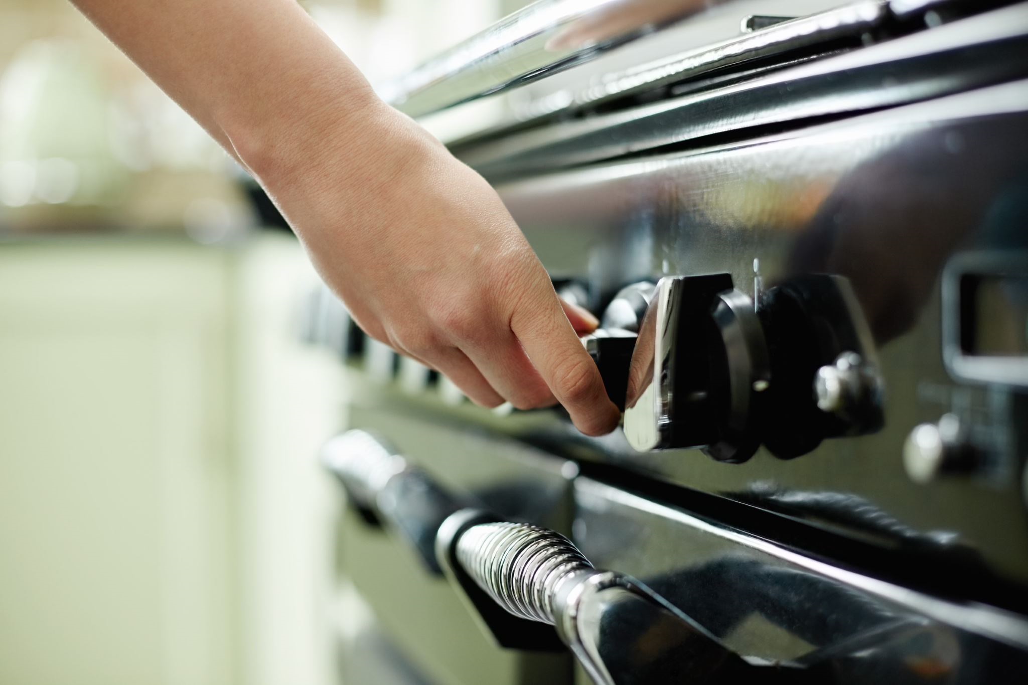 A hand adjusting a metallic style stove knob