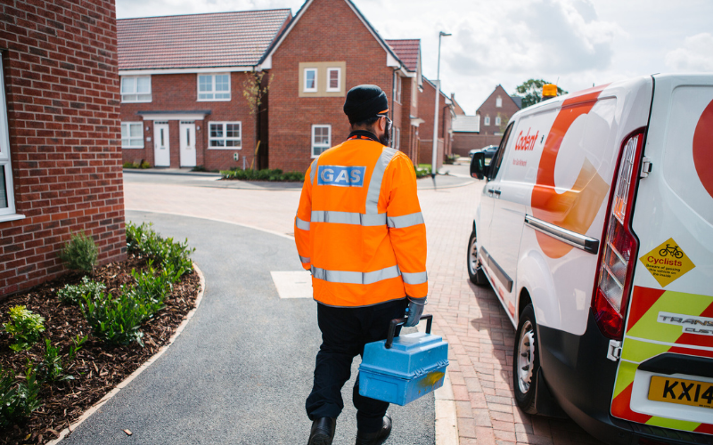 Gas engineer in high-visibility jacket walking toward a service van in a residential street