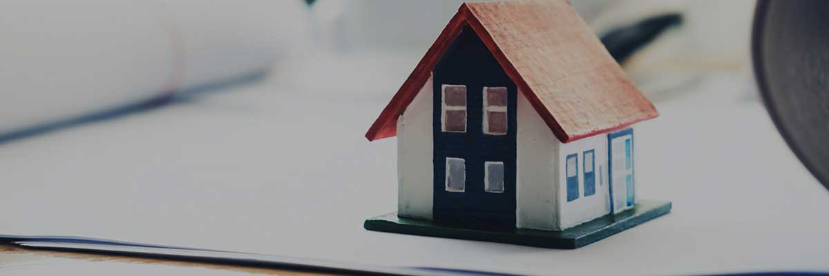 A small model house with a red roof and blue door, placed on white paper