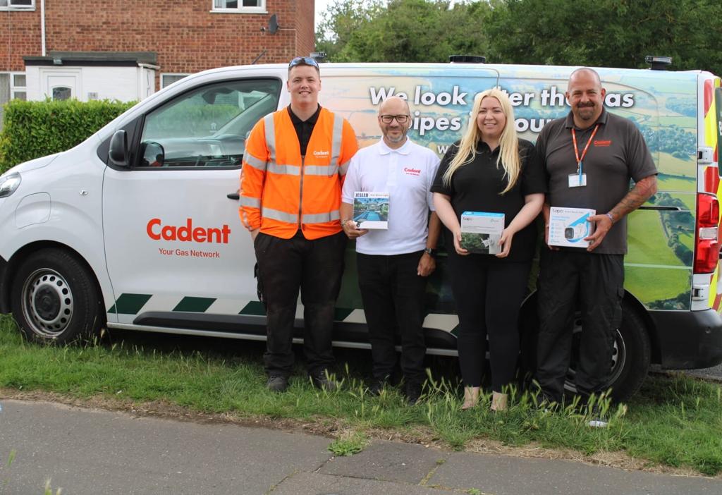 Four people stand smiling in front of a Cadent van with the logo 