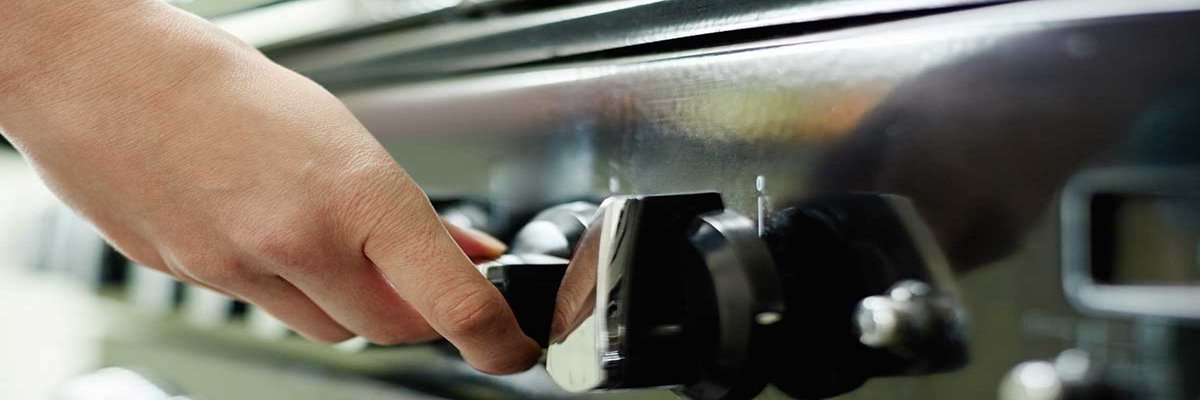 A hand adjusting a metallic style stove knob