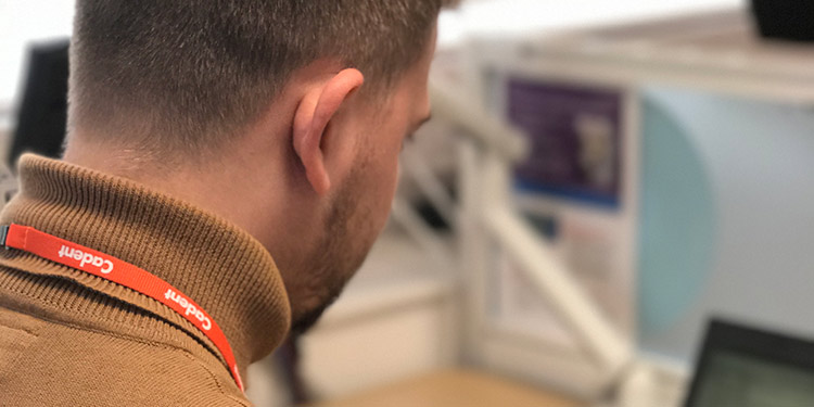 young-Cadent engineer-working near desk wearing Cadent ID