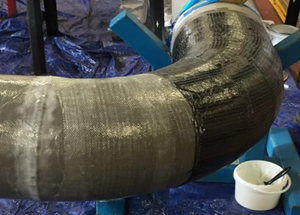 A close-up of a curved pipe wrapped in a gray protective material