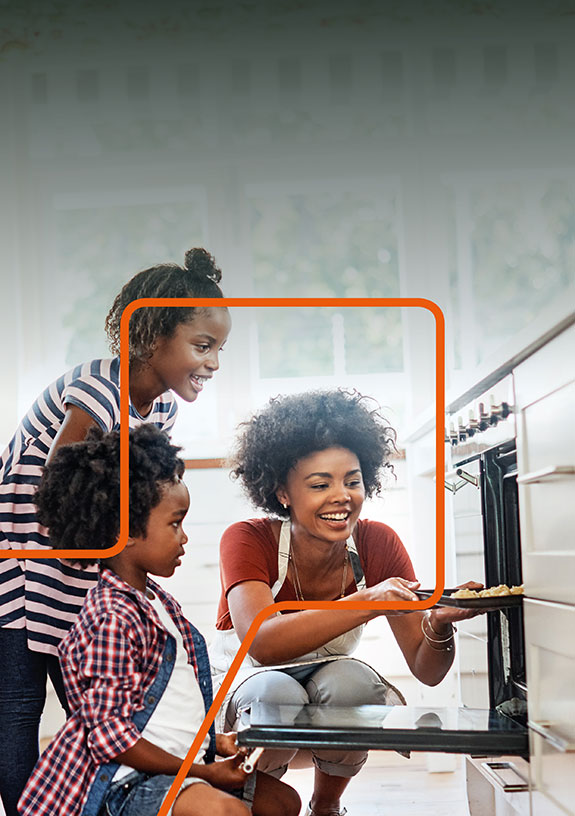 Cadent report cover image. Landscape image, left side is blank. Right side features a family in a kitchen, with the mother checking food inside the oven while her two children wait eagerly. Cadent branded orange line runs horizontally across the image.