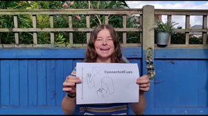 A person in front of a blue wall holds a sheet of paper titled 