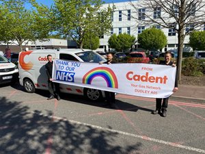 Three Cadent employees hold a banner reading 